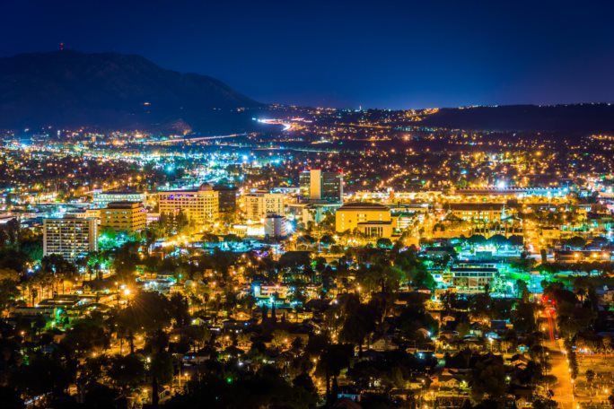 Villes américaines ayant la pire et la meilleure qualité de l’air – infographie de Palm Springs la nuit, montrant les lumières de la ville et les montagnes environnantes, reflétant une ville qui bénéficie de ciels relativement clairs mais qui fait encore face à des préoccupations occasionnelles quant à la qualité de l’air.
