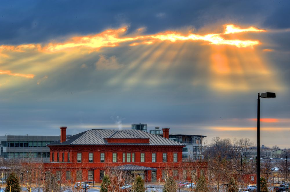 Sun rays breaking through clouds over historic buildings.