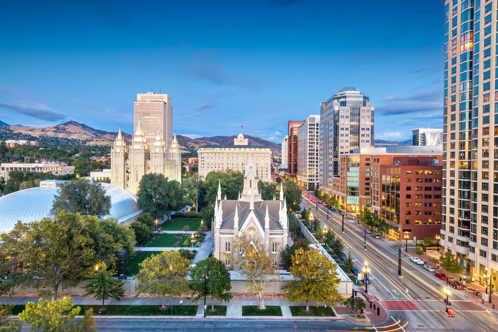 Salt Lake City, Utah skyline with historic buildings and mountain backdrop at dusk.
