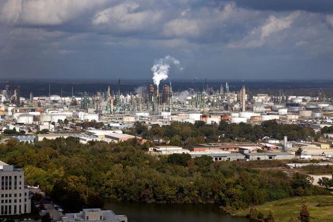 States and Counties With the Highest Rates of Lung Cancer - Infographics of An expansive oil refinery surrounded by urban and forested areas, showing industrial emissions in states with high energy consumption.