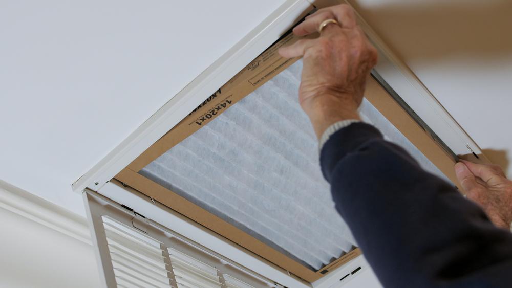 Everything You Need to Know About Heat Pump Filters  - Infographics of a man stalling indoor air filter.