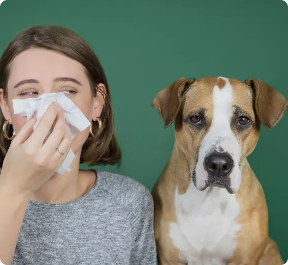 View of woman with allergies next to dog, showing pet dander impact.