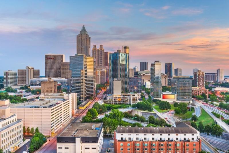 Cities With the Most Multigenerational Households - Aerial view of Atlanta's downtown skyline with skyscrapers, highways, and city streets under a colorful sky at dusk.