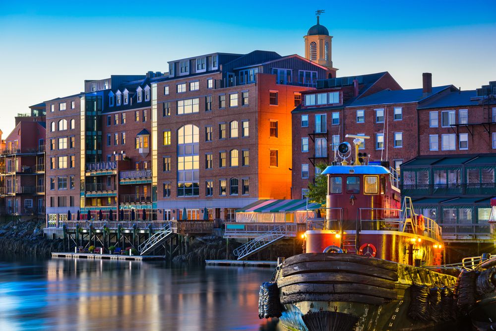 Portland's waterfront at dusk, showing buildings and a tugboat, highlighting areas that may house Korean War veterans in Maine.