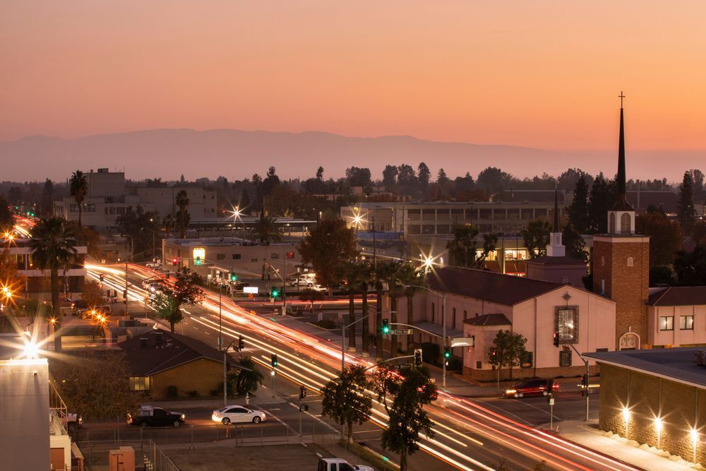 Paysage urbain de San Bernardino au crépuscule avec traînées lumineuses et montagnes en arrière‑plan.