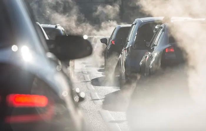Cars in heavy traffic emitting visible exhaust fumes, contributing to air pollution and poor outdoor air quality.