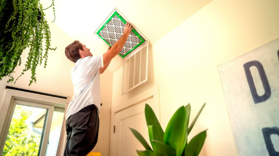 Man replacing a ceiling air filter in a residential HVAC return vent