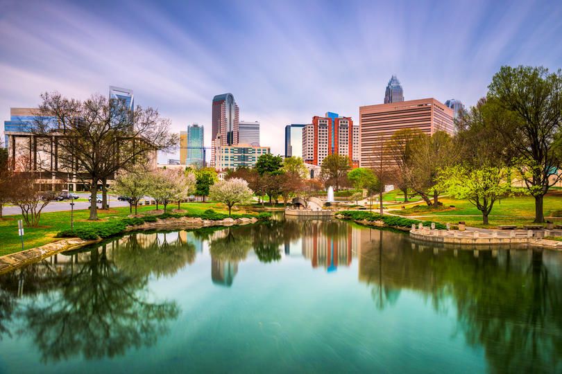 Modern skyline reflected in a tranquil city park pond with trees