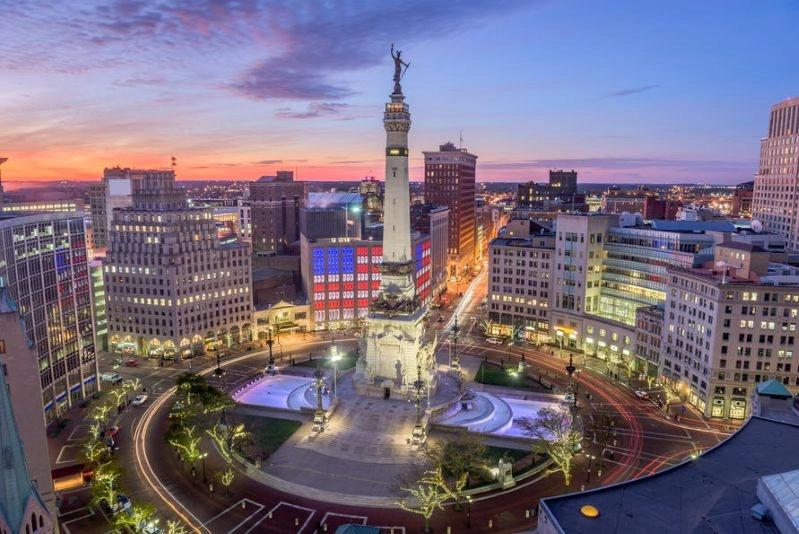 Cities with the Biggest Declines in Air Pollution - Image of a wide-angle shot of Indianapolis' Monument Circle with the skyline and colorful lights illuminating the area at dusk.