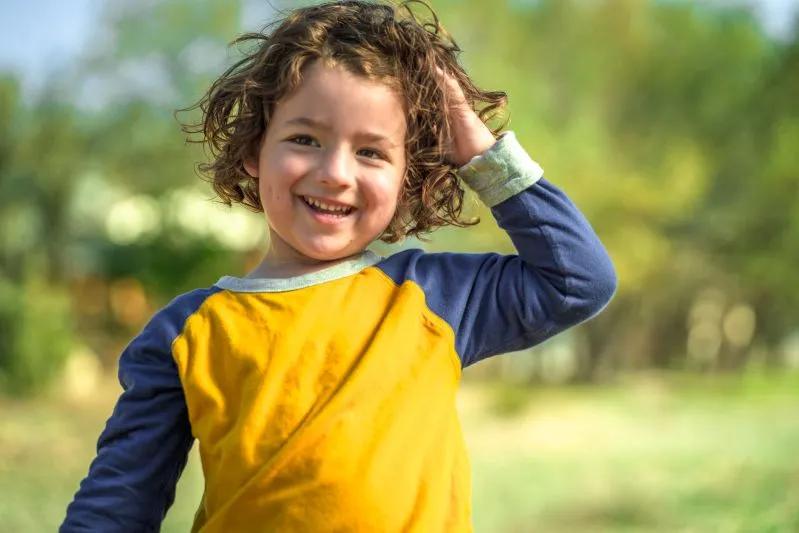 Can You Wash Air Purifier Filters - image of a smiling young boy with curly hair wearing a yellow and blue shirt.