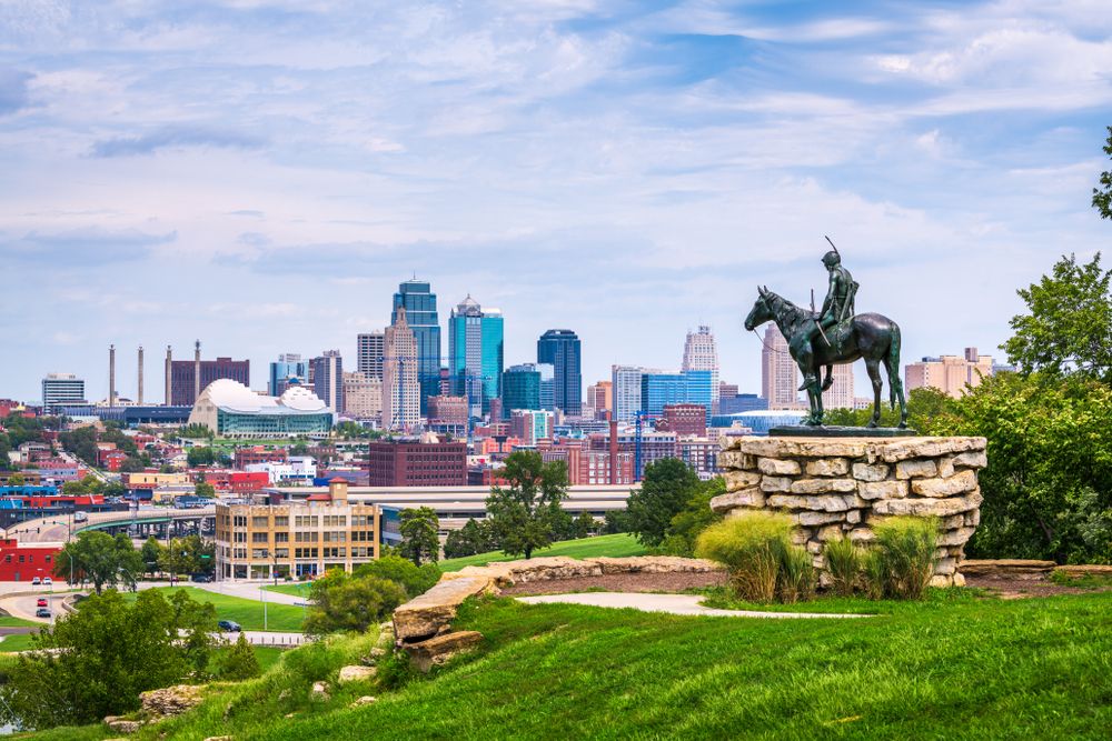 Kansas City skyline view with Native American scout statue in the foreground on a grassy hill