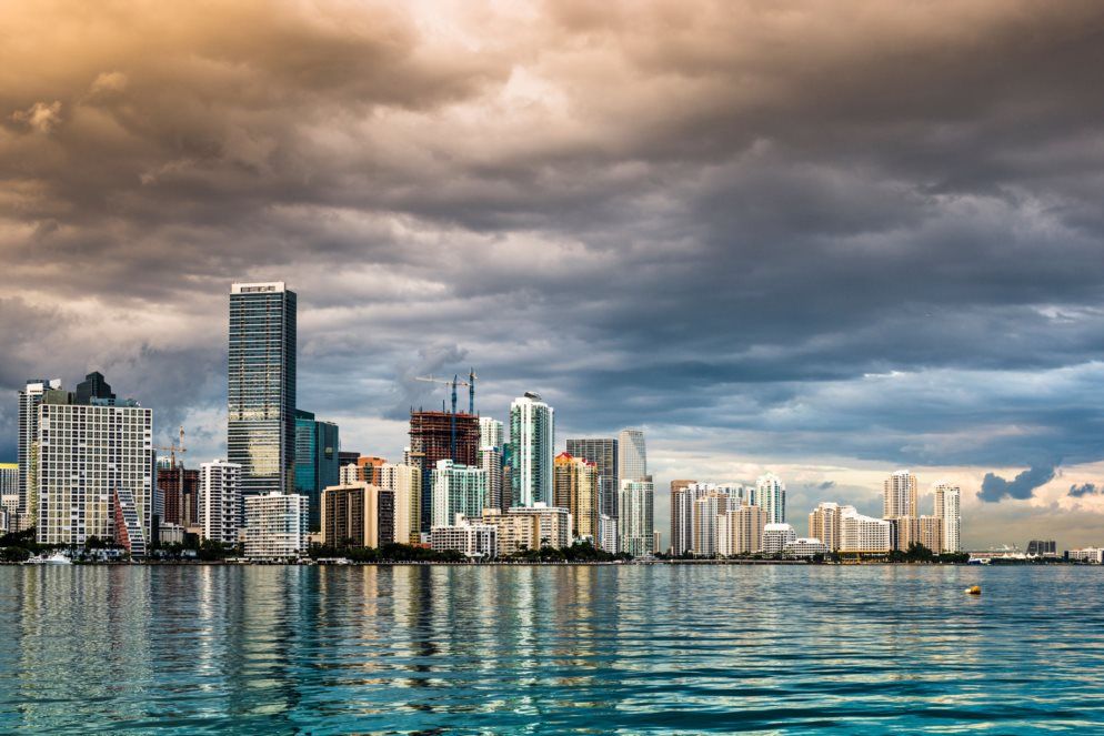 High-rise skyline with dramatic clouds over calm water