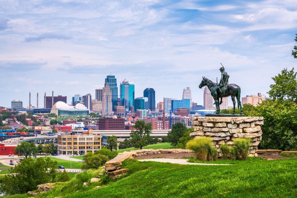Vue de la skyline de Kansas City avec la statue du scout amérindien au premier plan sur une colline herbeuse