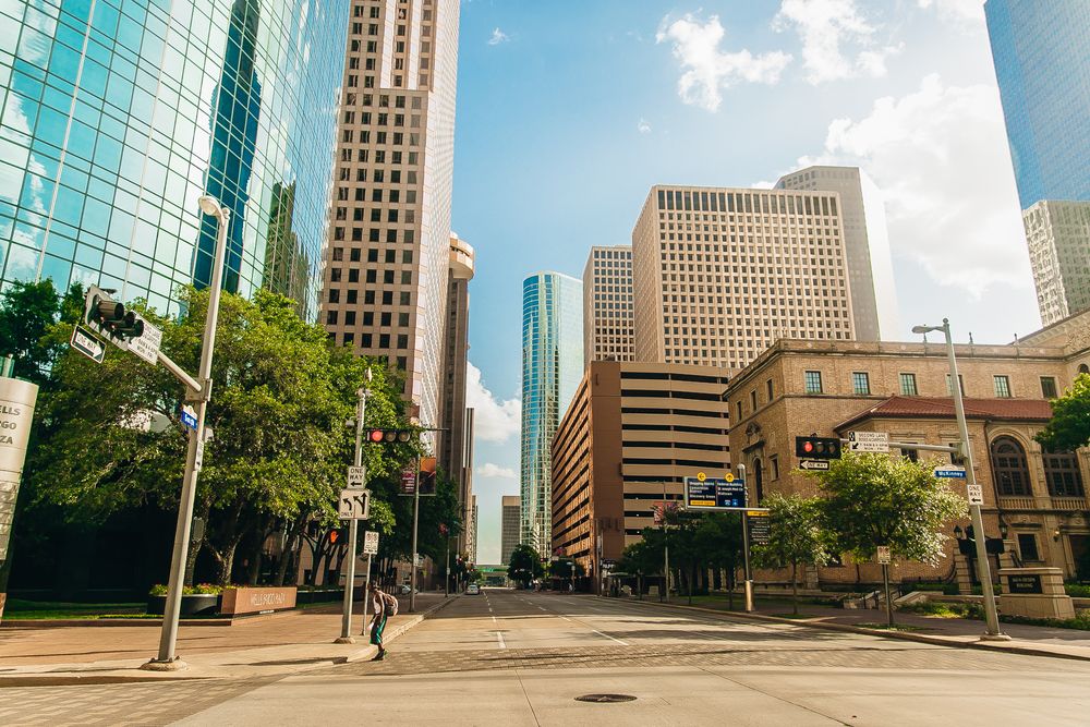Downtown Houston streetscape with modern skyscrapers under bright sunlight.