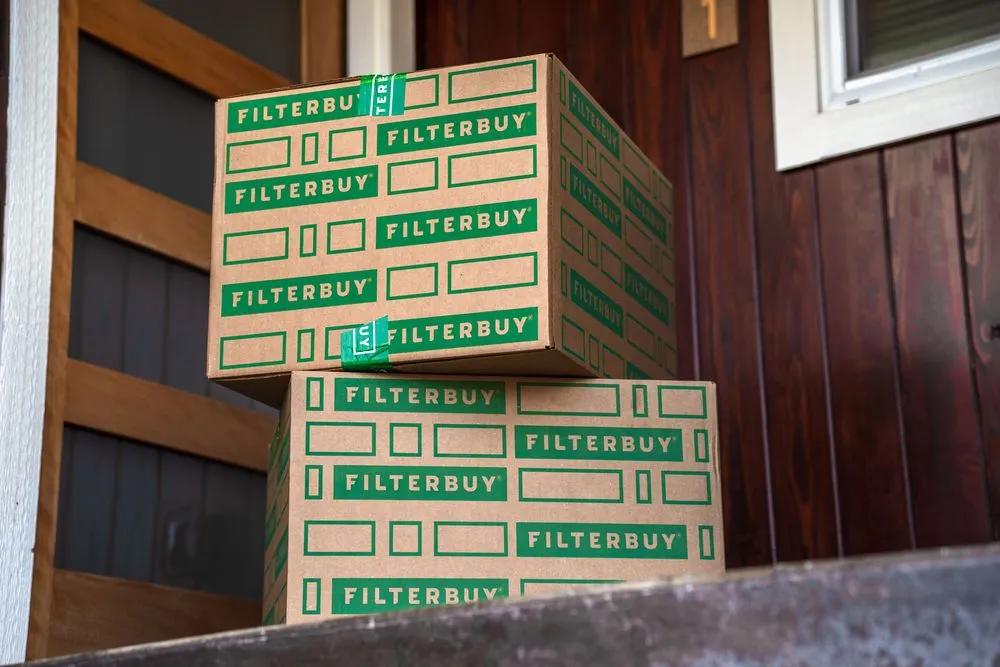  Image of three stacked newly delivered Filterbuy air vent filter boxes right at the customer's a front door.