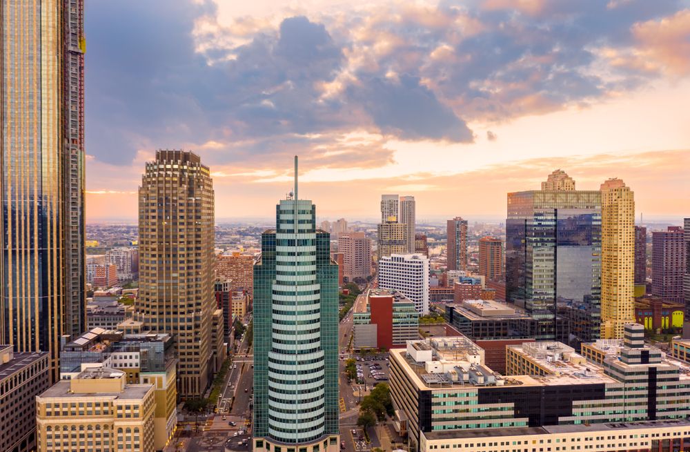 Aerial view of a modern city skyline at sunset, with a mix of tall buildings and vibrant skies.