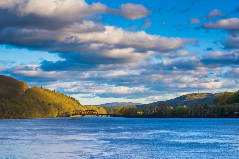 States and Counties With the Highest Rates of Lung Cancer - Infographics of a calm river and bridge in Vermont, representing states with low industrial activity and strong commitments to clean energy.