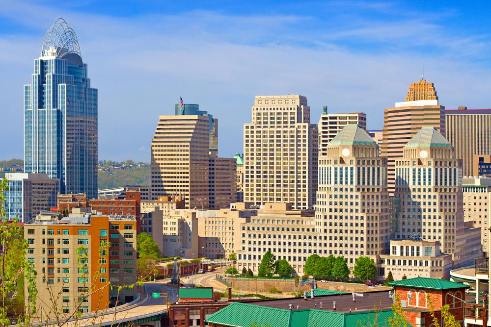 View of downtown Cincinnati with modern skyscrapers and historic architecture under a bright sky.