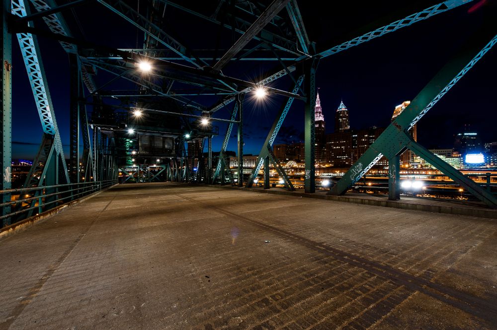 Night view of a steel bridge in Cleveland with city skyline in the background.