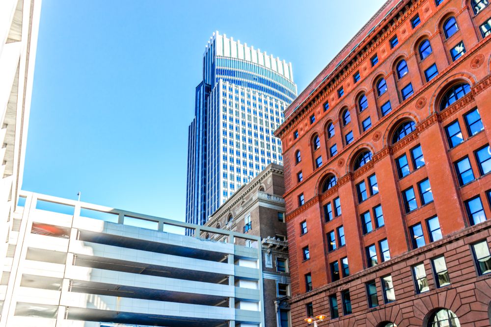  Modern skyscrapers and historic red brick building under a clear blue sky.