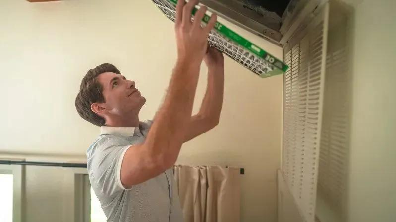 Where Is the Old Furnace Filter Located in Your Home? - image of a man installing a Filterbuy air filter in a ceiling vent.