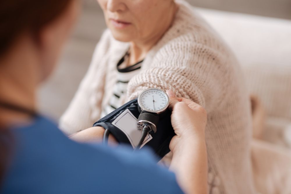 Healthcare worker measuring blood pressure of a senior woman at home