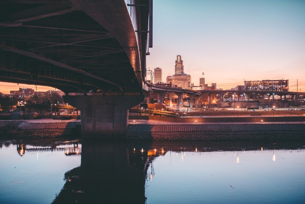 Ligne d’horizon d’Omaha, Nebraska, au coucher du soleil, vue depuis sous un pont, avec reflets dans la rivière