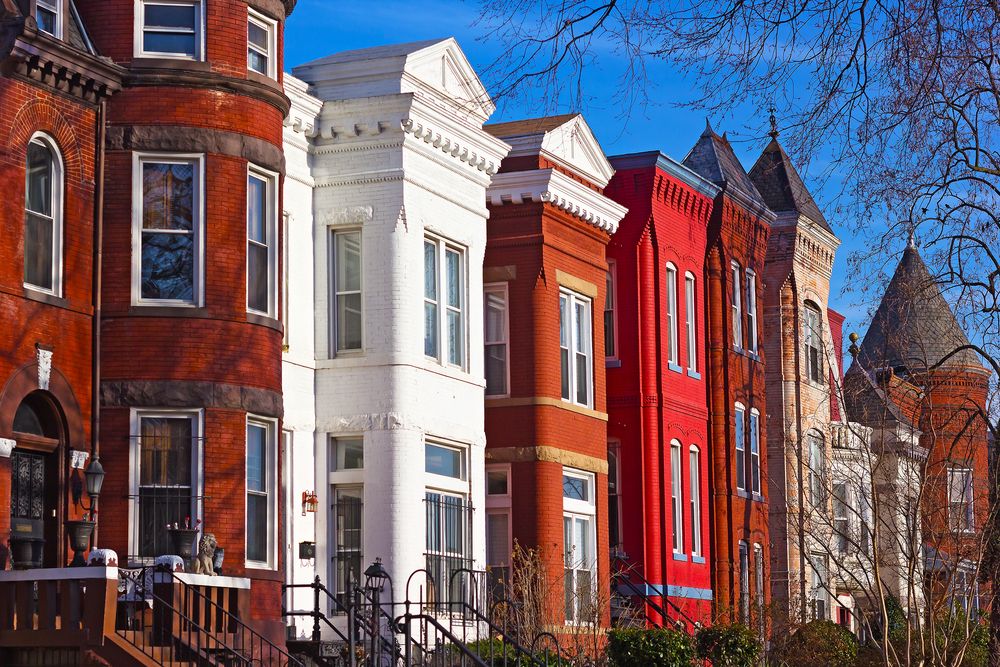 Row of colorful urban brownstone houses in sunlight.