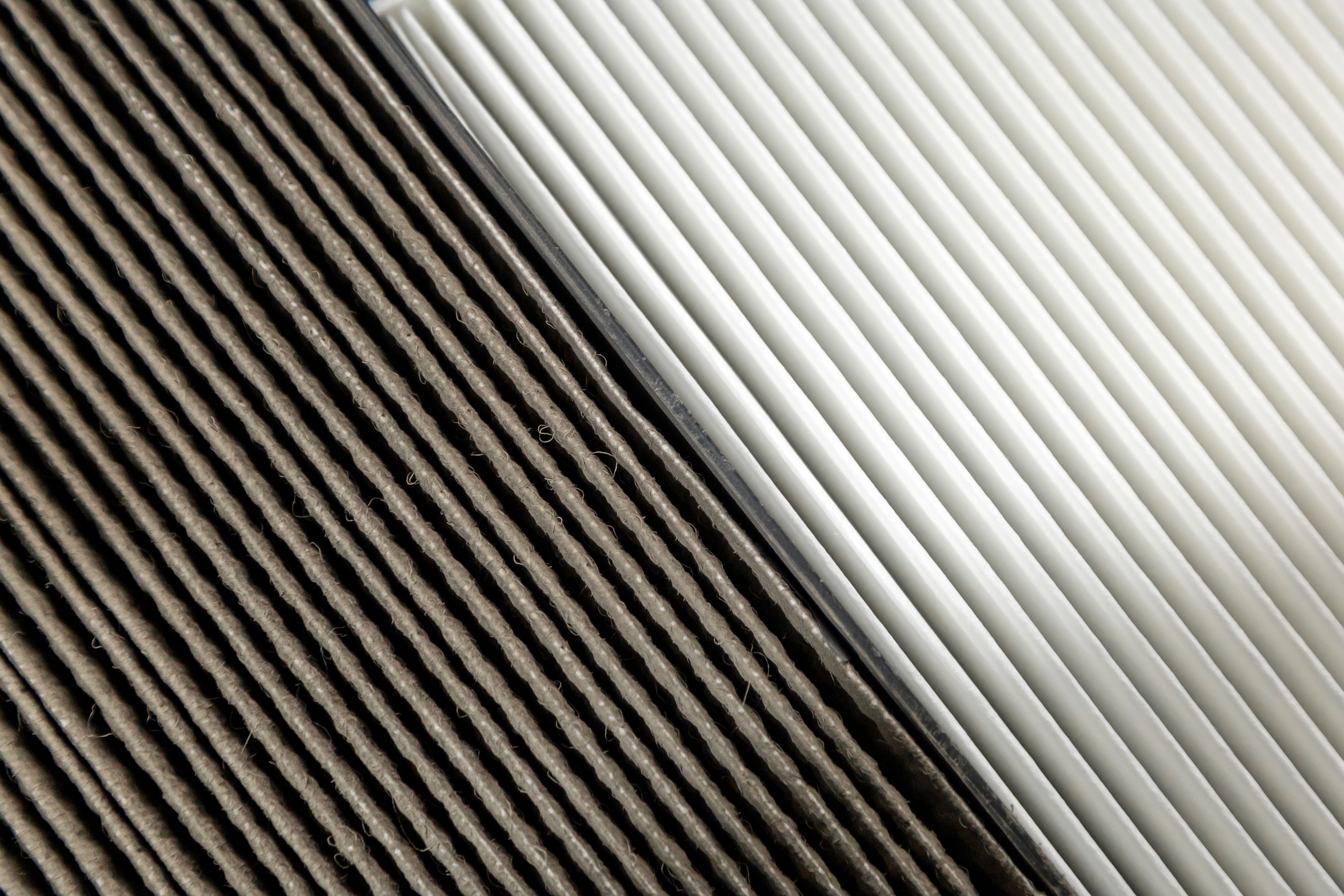 A close-up view of two air filters, one clean and white on the right, and the other dirty and darkened on the left, showing the difference in air filtration effectiveness.