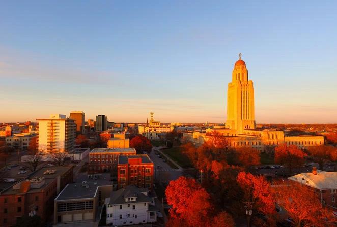 States and Counties With the Highest Rates of Lung Cancer - Infographics of a state capitol surrounded by autumn foliage, representing smaller states where emissions per capita vary based on energy sources.