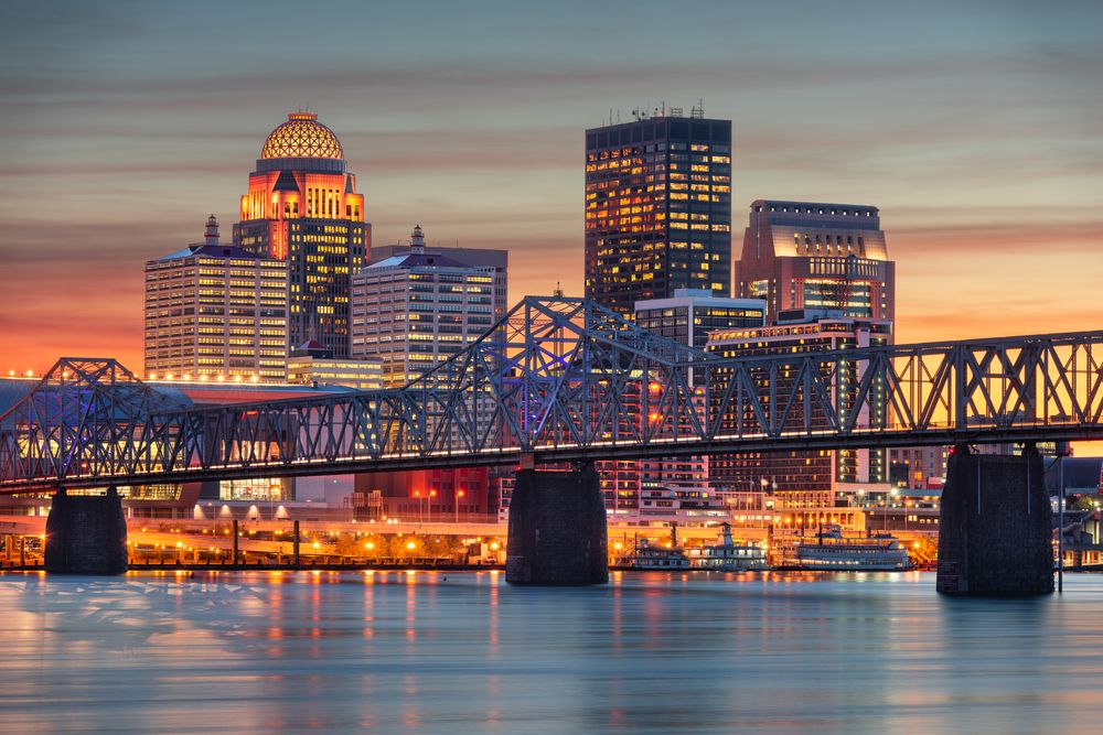 Twilight view of Louisville, Kentucky skyline with bridge and reflections over the river.