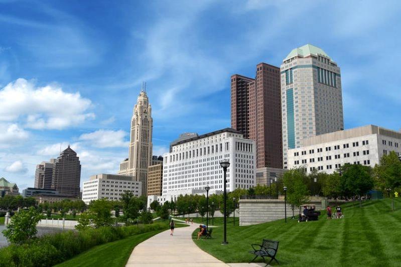 Cities Where Remote Workers Log the Most Hours - Images of the Columbus, Ohio skyline along the river, showing a vibrant green park and modern buildings against a bright sky.