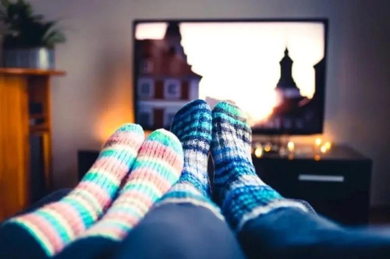 Image showing a couple's feet, both wearing socks, while relaxing in their living room.