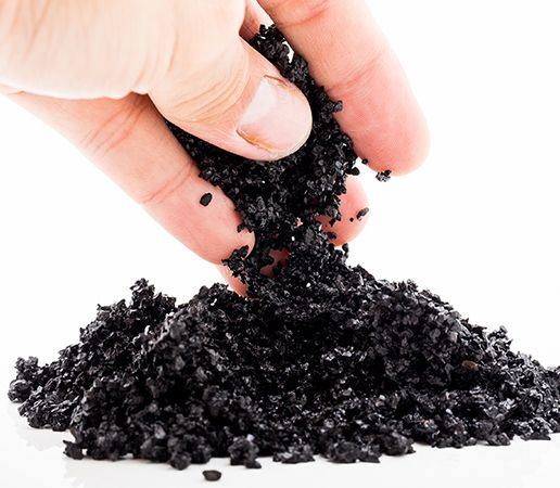 Hand holding granules of activated carbon used in air and water filtration systems