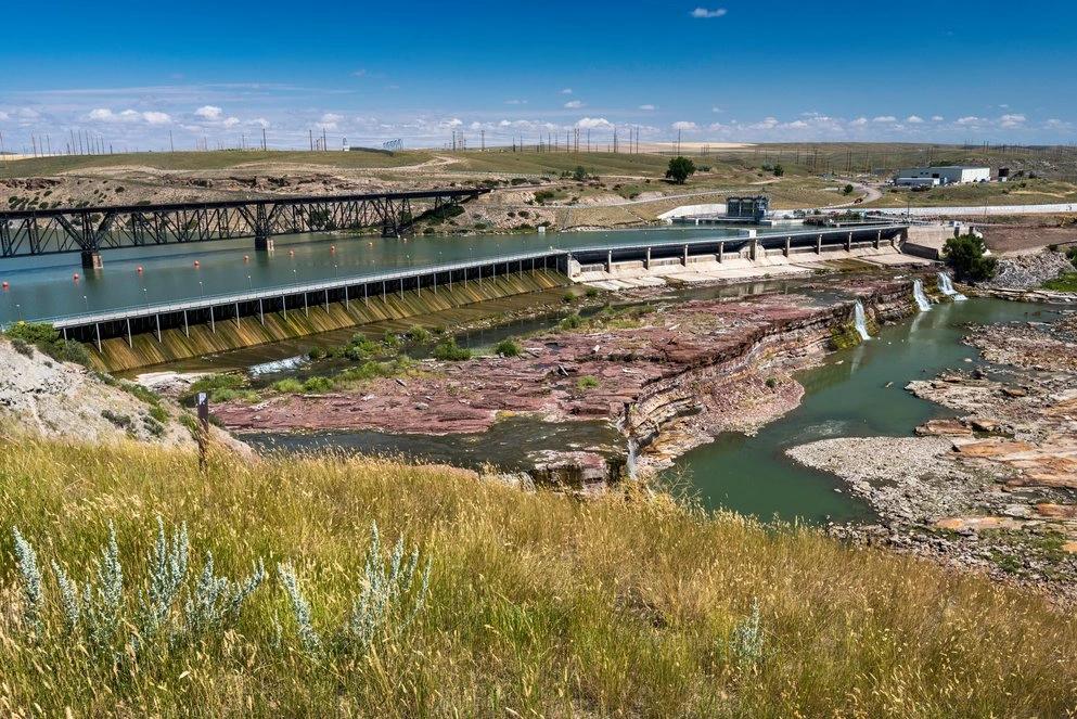 États et comtés ayant les taux les plus élevés de cancer du poumon : infographie d’un quai industriel dans un cadre naturel préservé, mettant en évidence l’infrastructure énergétique de l’Alaska et ses émissions par habitant modérées.