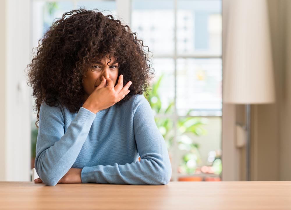 Imag of a woman covering her nose due to bad AC smell—related to common AC problems and solutions.