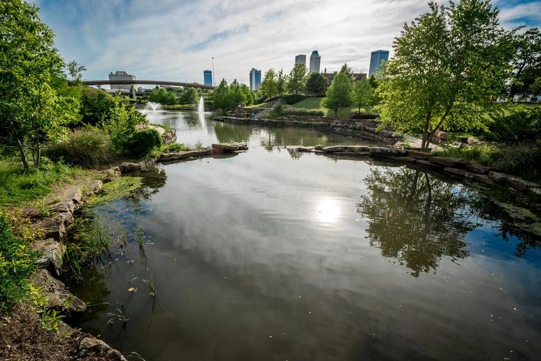 Villes ayant les populations les plus âgées — Infographie d’un parc urbain paisible avec un bassin réfléchissant, fréquent dans les villes aux populations les plus âgées, offrant aux retraités une échappée sereine.