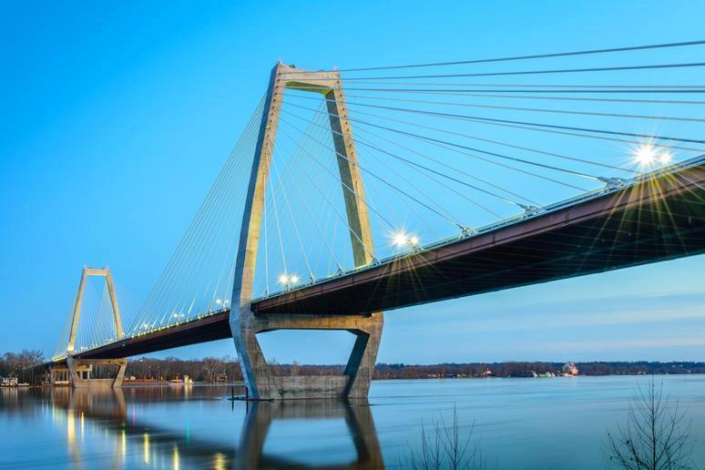 États et comtés ayant les taux les plus élevés de cancer du poumon : infographie d’un pont suspendu illuminé au crépuscule, symbolisant l’infrastructure contribuant aux émissions liées aux transports dans les États urbanisés.