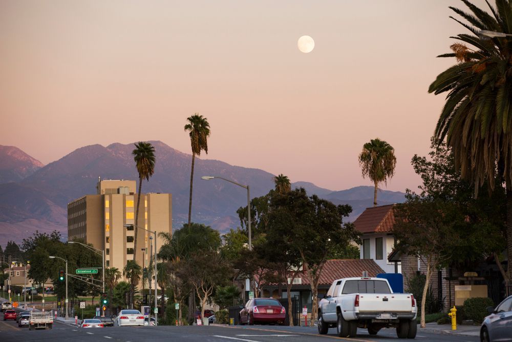 Vue de rue à San Bernardino au crépuscule avec des palmiers et des montagnes en arrière‑plan.