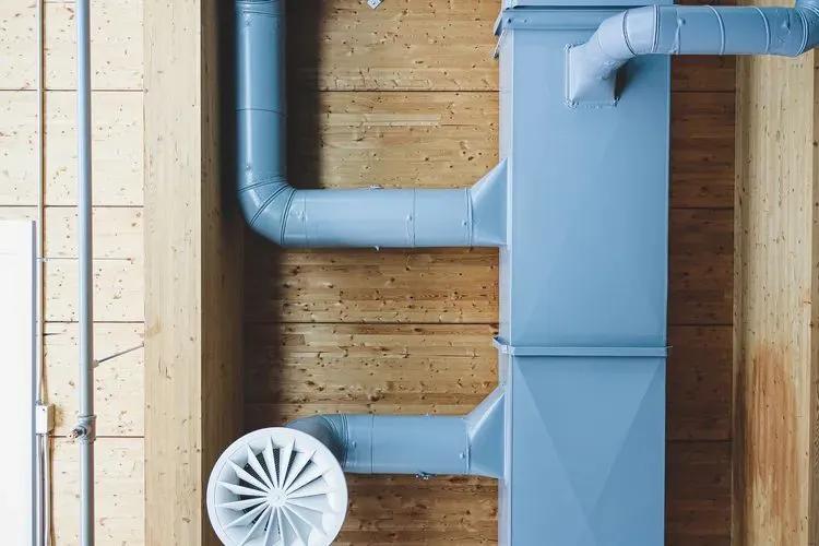 Image d’un réseau de conduits CVC apparent fixé sur un mur en bois, illustrant un design moderne de ventilation et de circulation d’air.