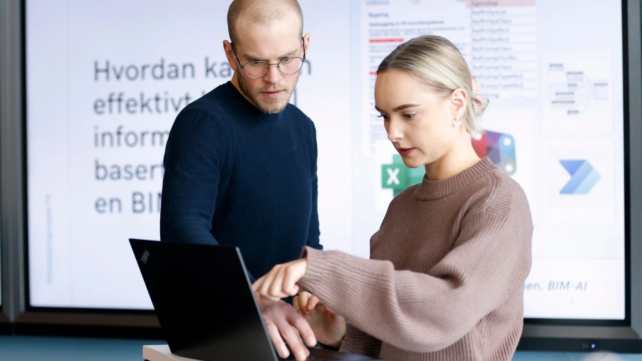 To studenter diskuterer foran en datamaskin