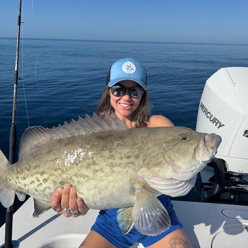 Angler in a ball cap holding a heavy gag grouper beside the outboard on a Gulf of Mexico charter