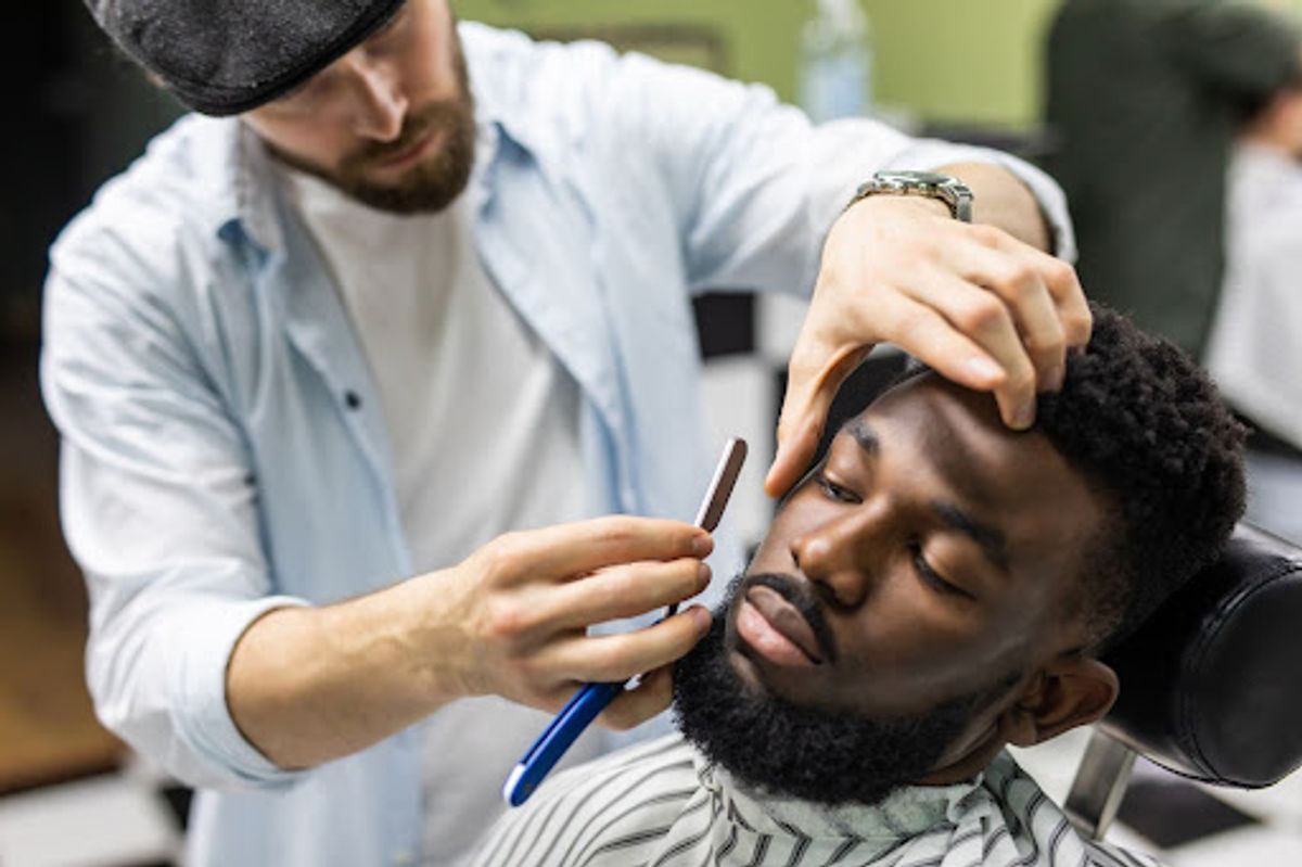 Barber using a straight razor on a client's beard.