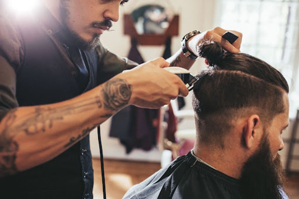 Barber carefully trimming client's hair.