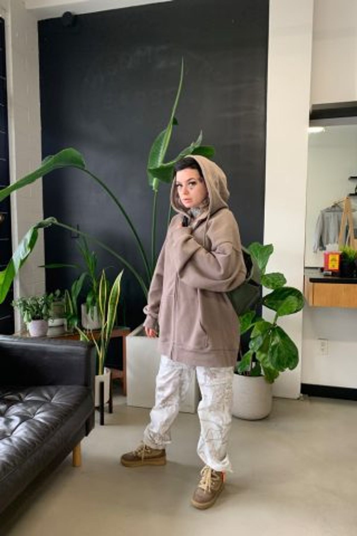 Person in a hoodie standing in a stylish barbershop.