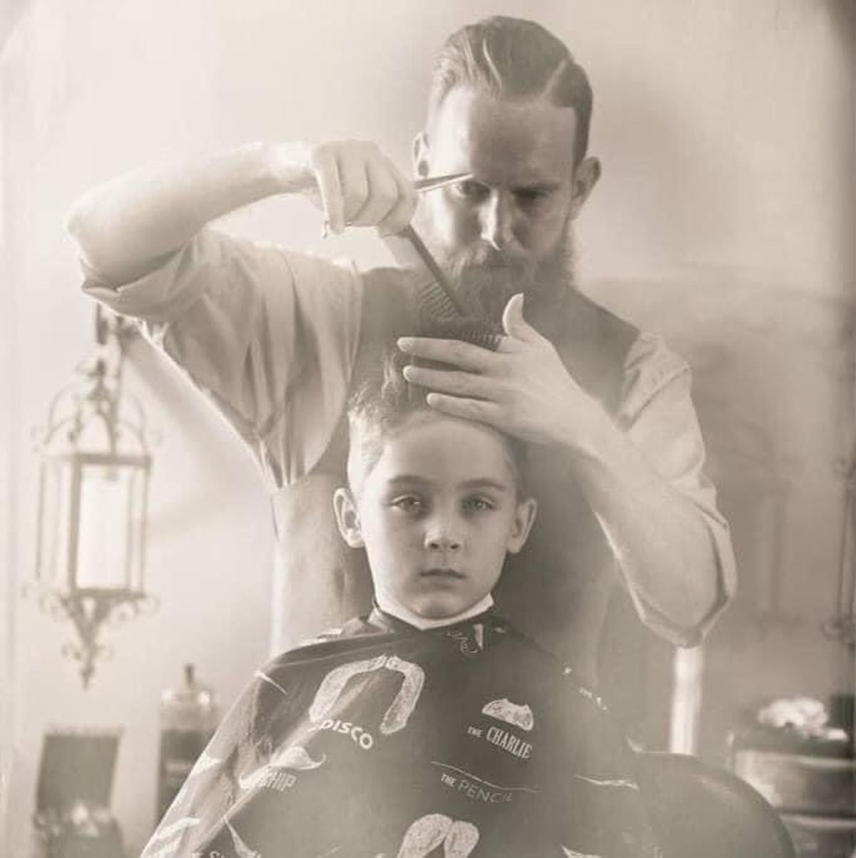 Barber giving boy a haircut in vintage style.