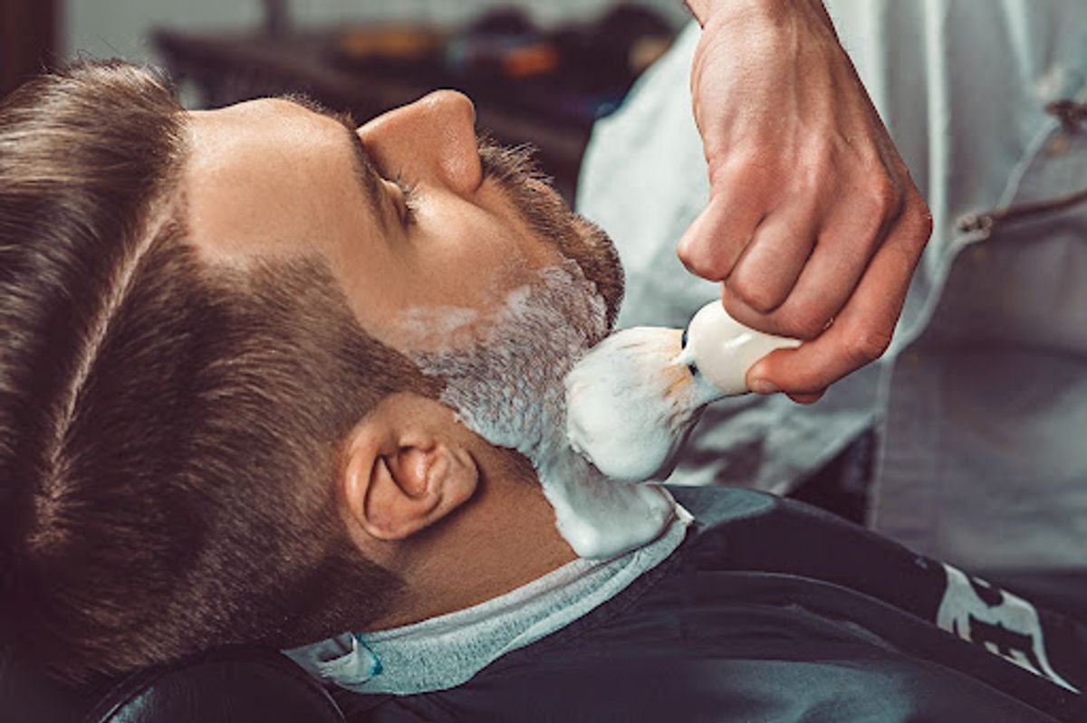 Applying shaving cream to a client's face.