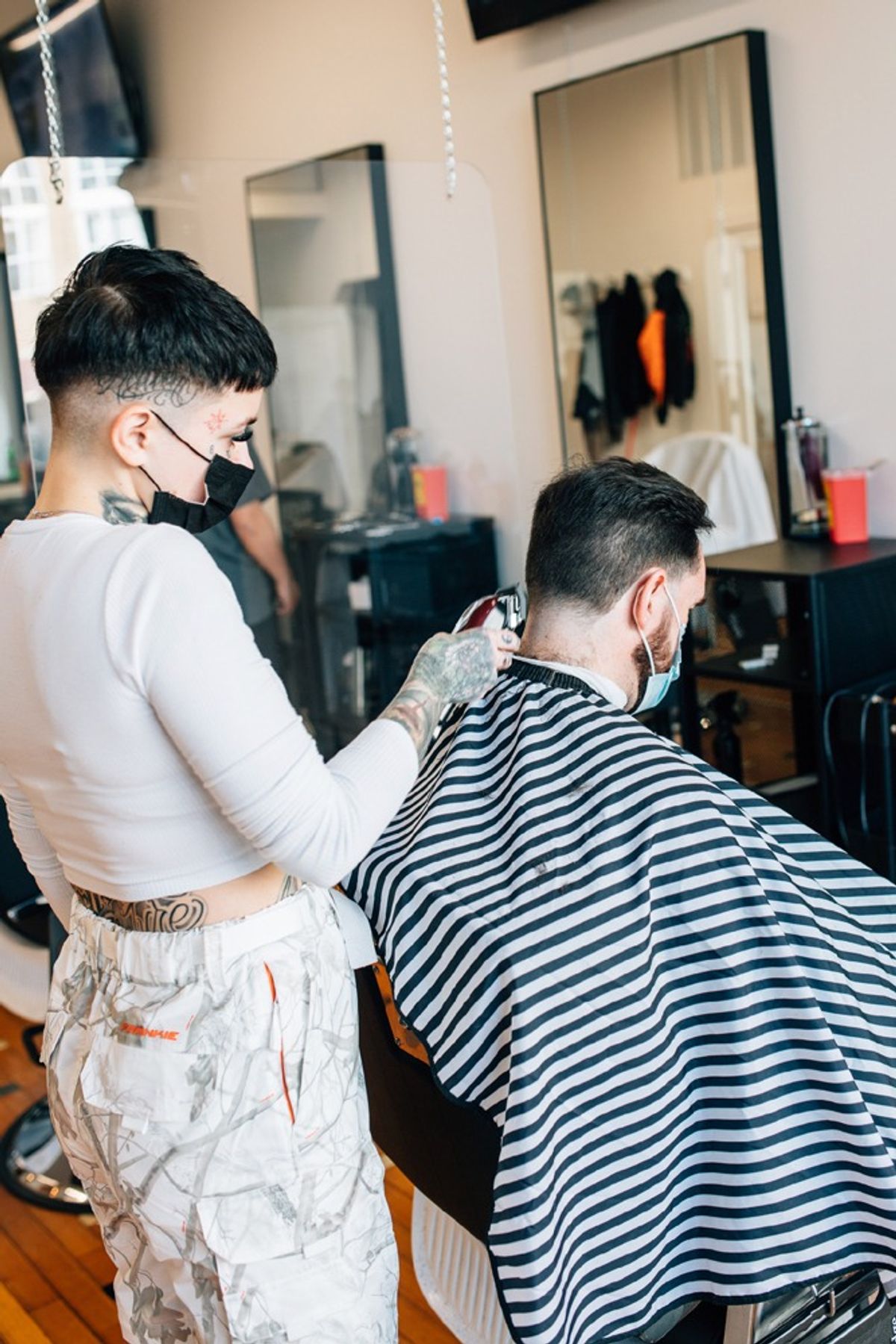 Barber cutting client's hair with clippers.
