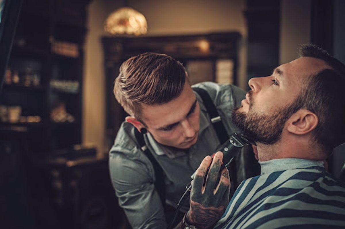 Barber carefully shaping a client's beard.
