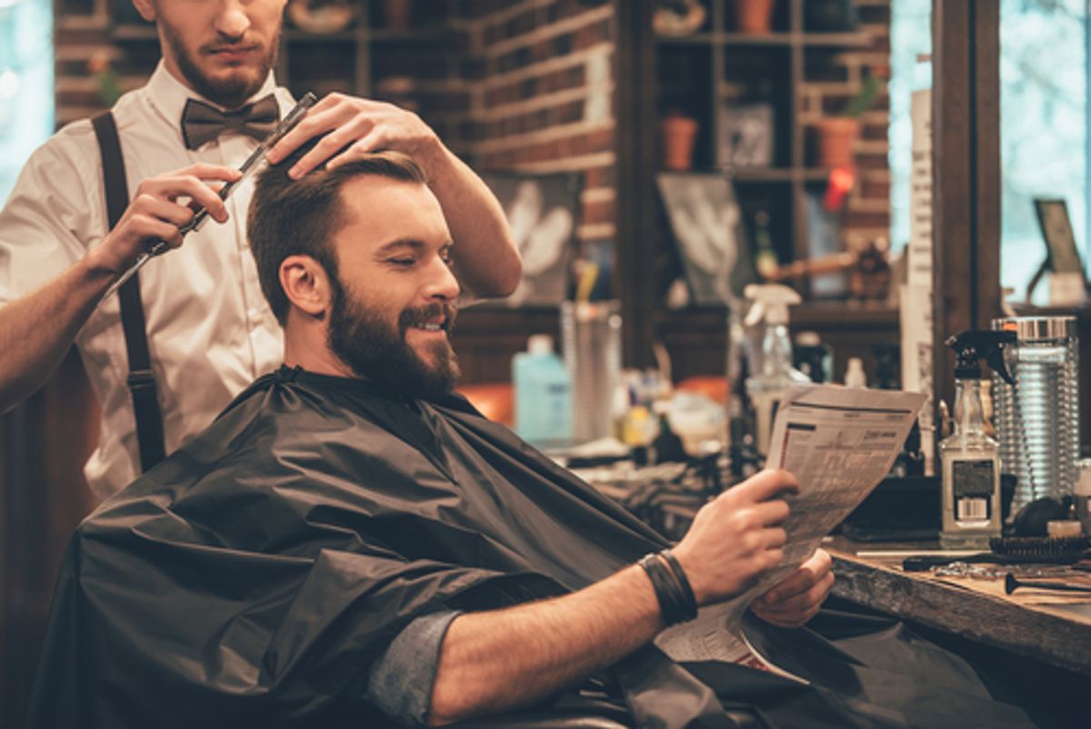 Barber cutting hair while client reads newspaper.